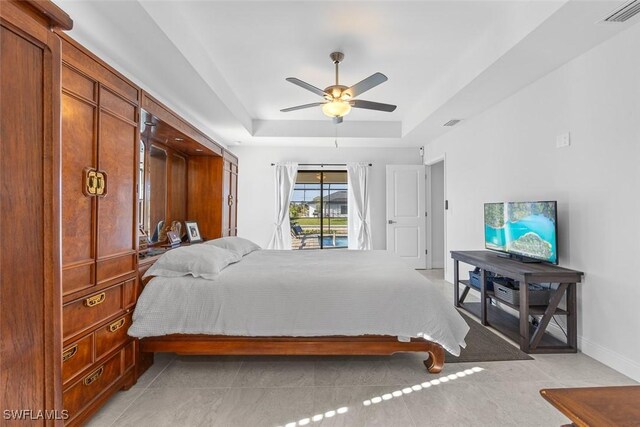 bedroom featuring ceiling fan, light tile patterned floors, and a tray ceiling