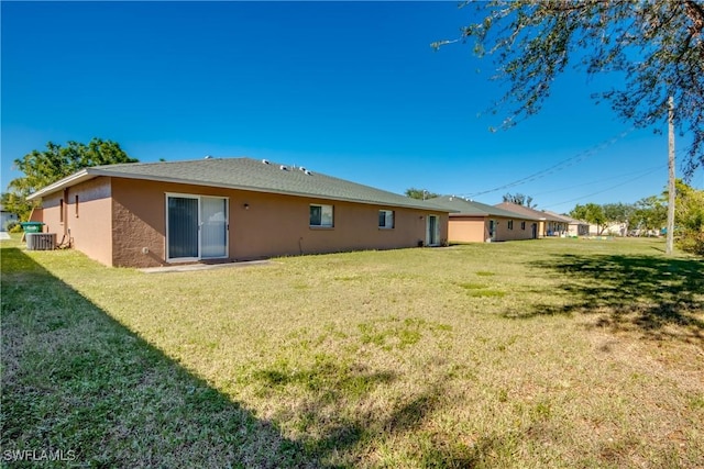 rear view of property with cooling unit and a lawn