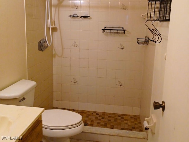 bathroom with vanity, tiled shower, and toilet