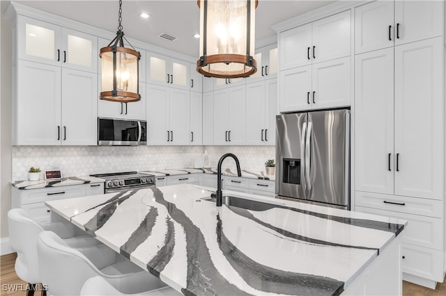 kitchen with pendant lighting, a kitchen breakfast bar, a kitchen island with sink, and appliances with stainless steel finishes