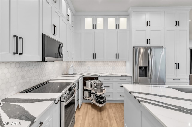 kitchen with light stone countertops, appliances with stainless steel finishes, light hardwood / wood-style flooring, and white cabinetry