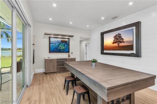 dining space featuring a healthy amount of sunlight, a water view, and light hardwood / wood-style floors