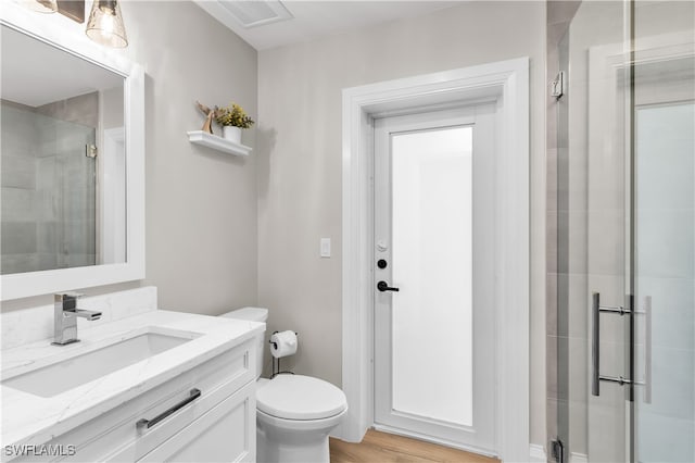 bathroom with wood-type flooring, vanity, a shower with shower door, and toilet