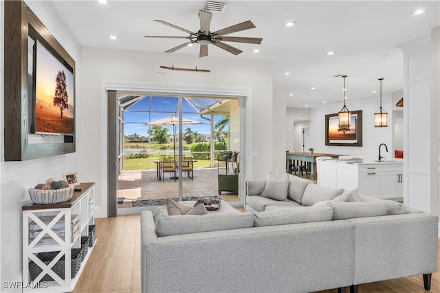 living room with light hardwood / wood-style flooring, ceiling fan, and sink