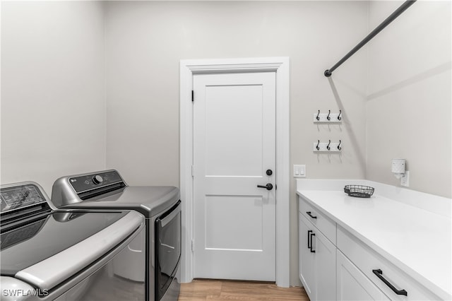 washroom with cabinets, light hardwood / wood-style floors, and washing machine and dryer