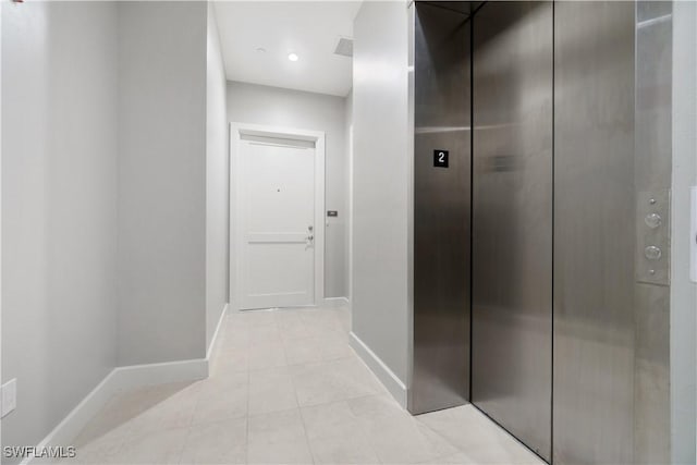 hall featuring light tile patterned floors and elevator