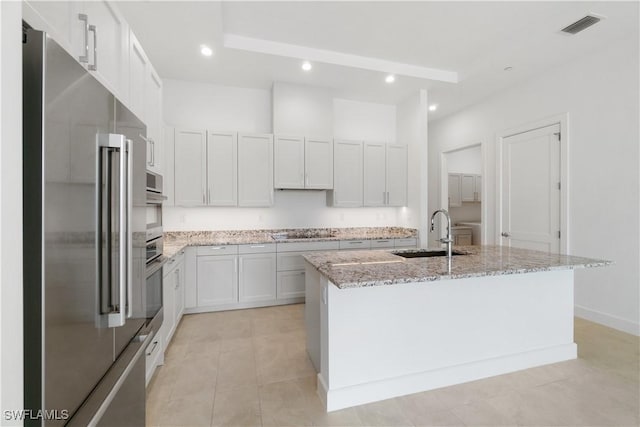 kitchen featuring sink, white cabinetry, appliances with stainless steel finishes, and a center island with sink