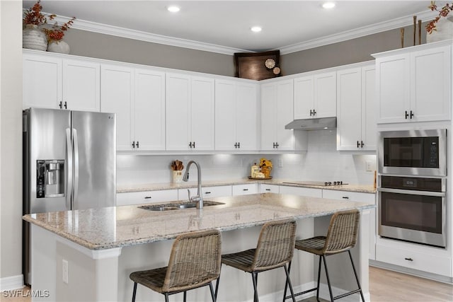 kitchen with white cabinets, stainless steel appliances, a center island with sink, and sink