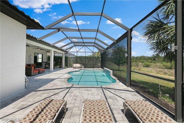 view of swimming pool with glass enclosure, ceiling fan, and a patio area