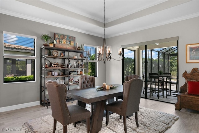 dining room featuring a raised ceiling, crown molding, light hardwood / wood-style floors, and a notable chandelier