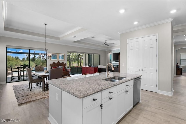 kitchen with light stone countertops, ornamental molding, a kitchen island with sink, sink, and white cabinetry