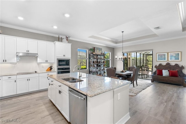 kitchen featuring appliances with stainless steel finishes, a raised ceiling, sink, a center island with sink, and white cabinets