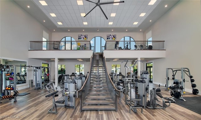 gym featuring ceiling fan, hardwood / wood-style floors, and a towering ceiling