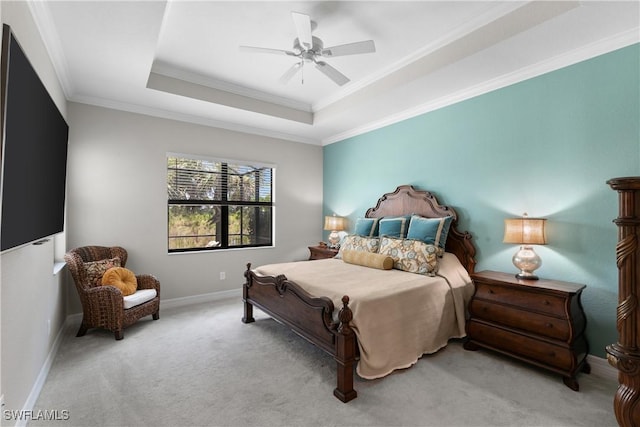 carpeted bedroom with a tray ceiling, ceiling fan, and ornamental molding