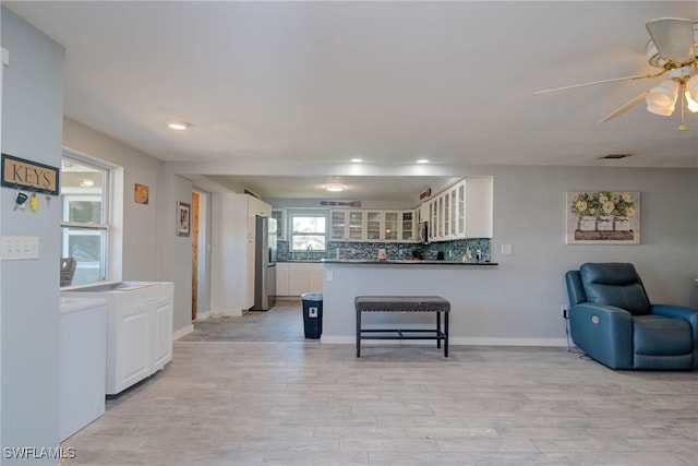 kitchen featuring white cabinets, decorative backsplash, stainless steel fridge, and light wood-type flooring