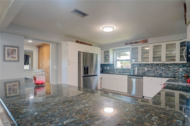 kitchen featuring backsplash, white cabinets, dark stone counters, and appliances with stainless steel finishes