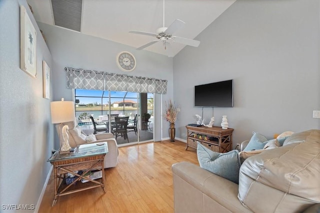 living room with hardwood / wood-style floors, ceiling fan, and high vaulted ceiling