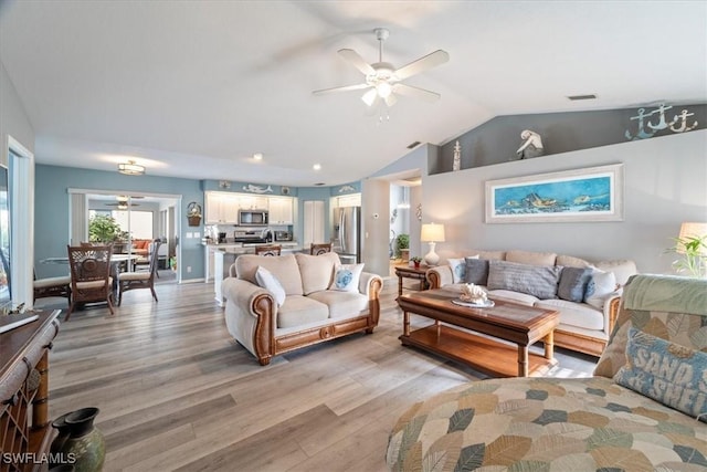 living room featuring ceiling fan, light hardwood / wood-style flooring, and vaulted ceiling