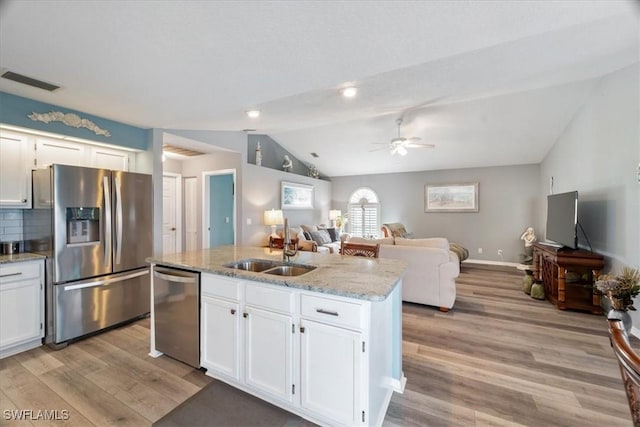 kitchen with ceiling fan, white cabinetry, tasteful backsplash, an island with sink, and appliances with stainless steel finishes