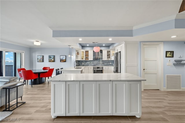 kitchen with decorative backsplash, light stone counters, stainless steel appliances, white cabinets, and hanging light fixtures