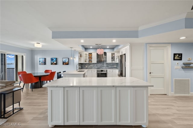 kitchen with tasteful backsplash, white cabinetry, stainless steel appliances, and decorative light fixtures