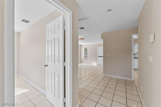 hallway with light tile patterned floors, baseboards, and visible vents