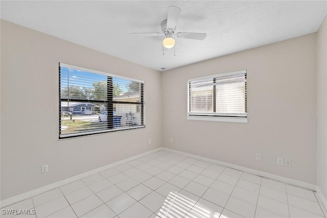 empty room with plenty of natural light, a ceiling fan, baseboards, and a textured ceiling