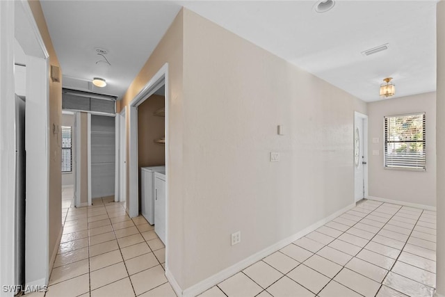 corridor with visible vents, baseboards, independent washer and dryer, and light tile patterned flooring