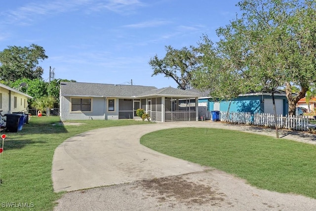 ranch-style home featuring fence, a sunroom, stucco siding, concrete driveway, and a front lawn