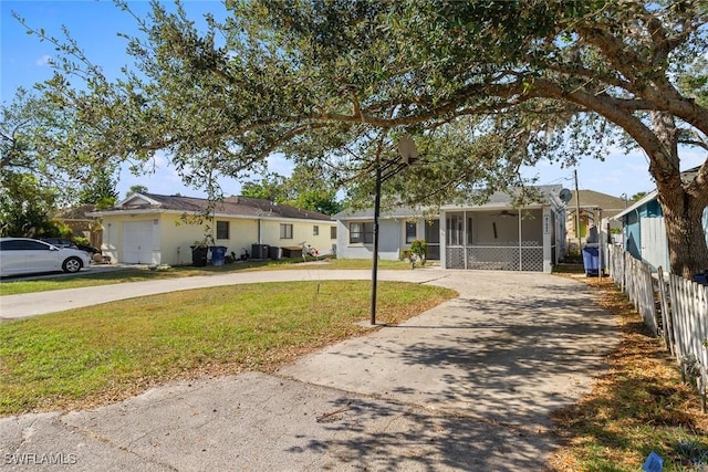 ranch-style home with concrete driveway, fence, a front yard, and ceiling fan