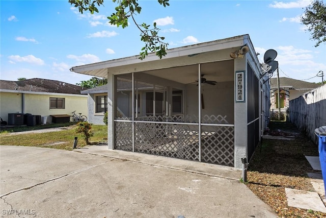 view of front of house featuring ceiling fan, fence, central AC, and a sunroom