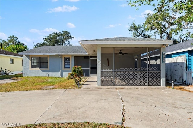 view of front of home featuring an attached carport, fence, concrete driveway, stucco siding, and a sunroom