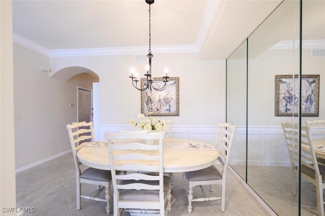 tiled dining area with an inviting chandelier and ornamental molding