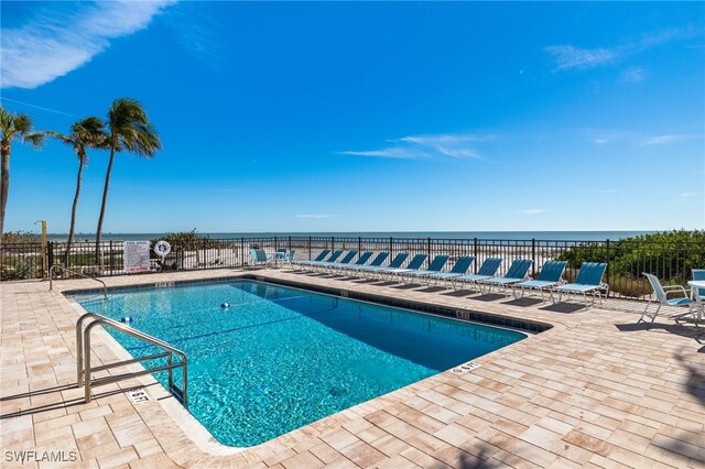 view of swimming pool featuring a patio and a water view