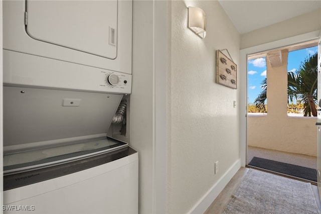 laundry room featuring stacked washer and clothes dryer and light wood-type flooring