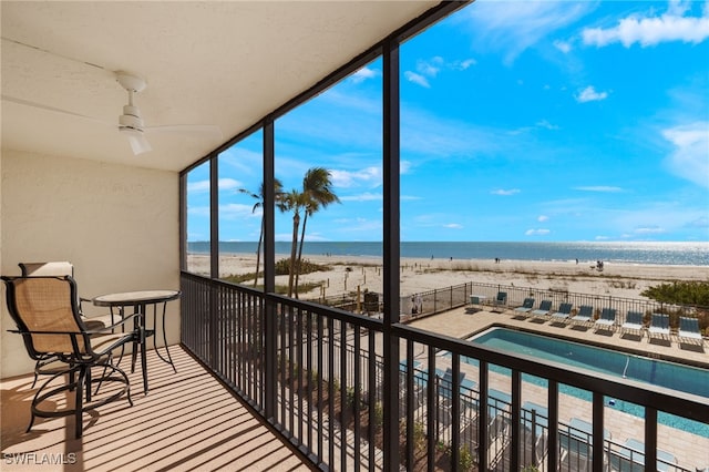 balcony featuring a view of the beach, a water view, and ceiling fan