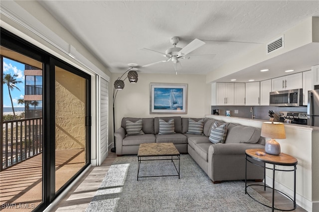 living room with ceiling fan and light hardwood / wood-style flooring