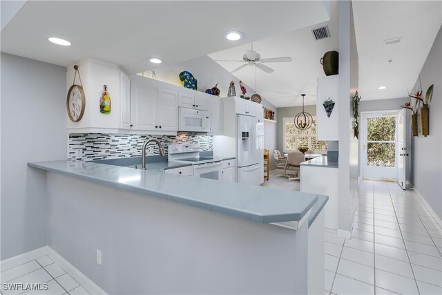 kitchen with white appliances, backsplash, lofted ceiling, white cabinets, and kitchen peninsula