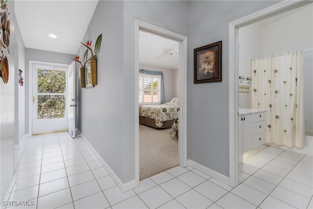 corridor with light carpet, baseboards, and light tile patterned floors