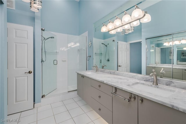 bathroom featuring double vanity, a stall shower, tile patterned flooring, and a sink