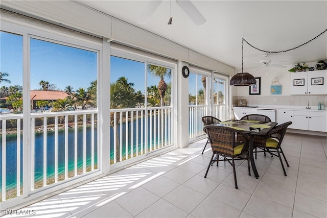 sunroom featuring a ceiling fan and a water view