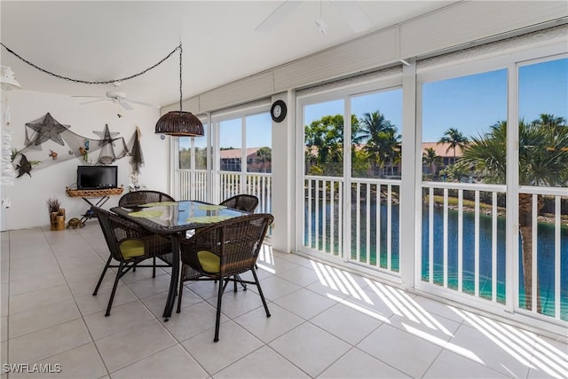 dining room with a ceiling fan, a water view, and light tile patterned flooring