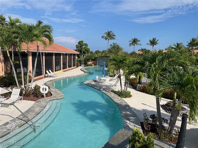 pool with a patio area, fence, and a sunroom