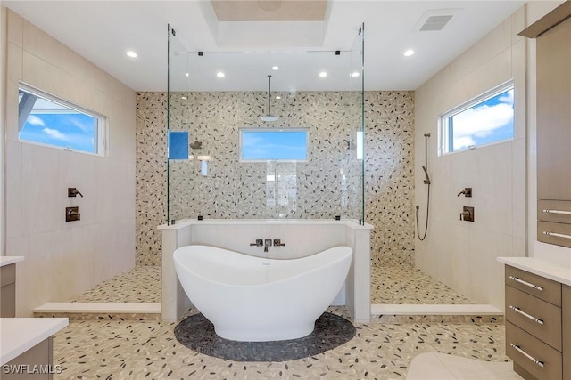 bathroom with tile patterned flooring, vanity, tile walls, and shower with separate bathtub