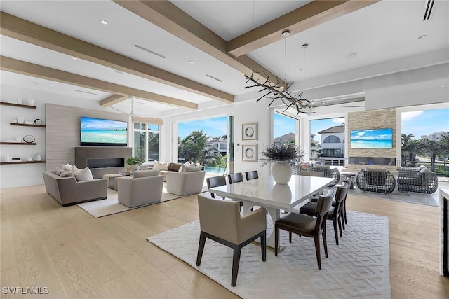 dining area with a wealth of natural light, light hardwood / wood-style flooring, beamed ceiling, and a chandelier