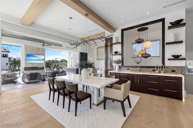 dining area with sink, beamed ceiling, and light hardwood / wood-style floors