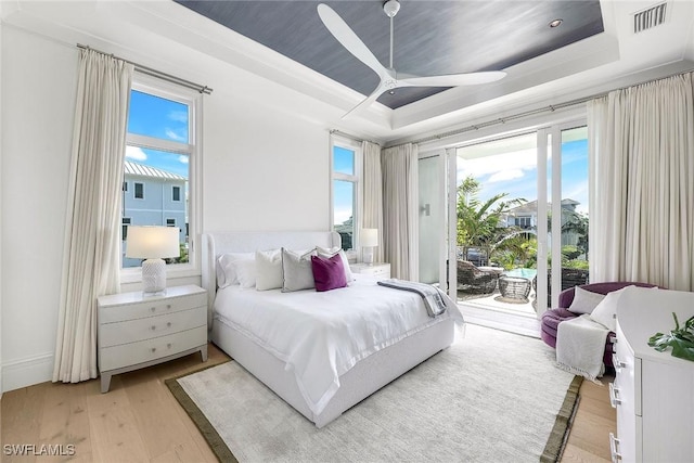 bedroom featuring ceiling fan, a raised ceiling, access to outside, and light hardwood / wood-style flooring