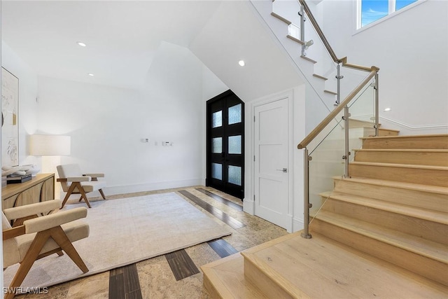 entrance foyer with french doors, a towering ceiling, and light hardwood / wood-style floors