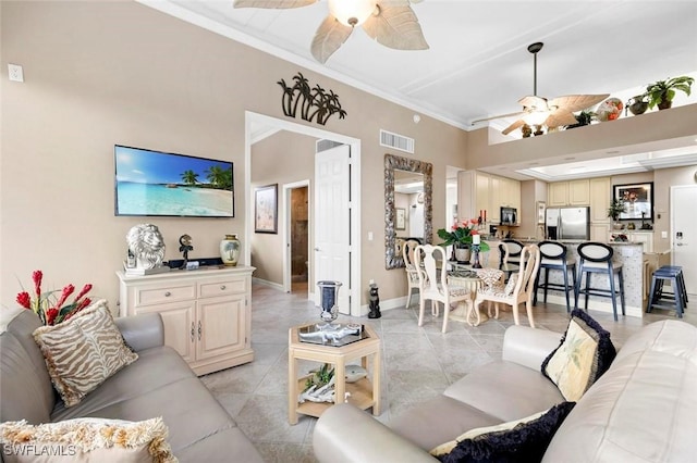 living room with visible vents, baseboards, ornamental molding, and a ceiling fan