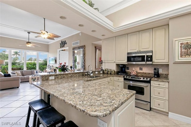 kitchen featuring a kitchen bar, kitchen peninsula, stainless steel appliances, crown molding, and sink